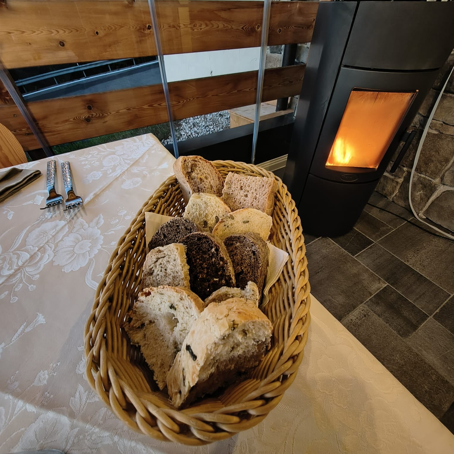 Cestino di pane assortito sulla tavola accanto alla stufa nella terrazza riscaldata
