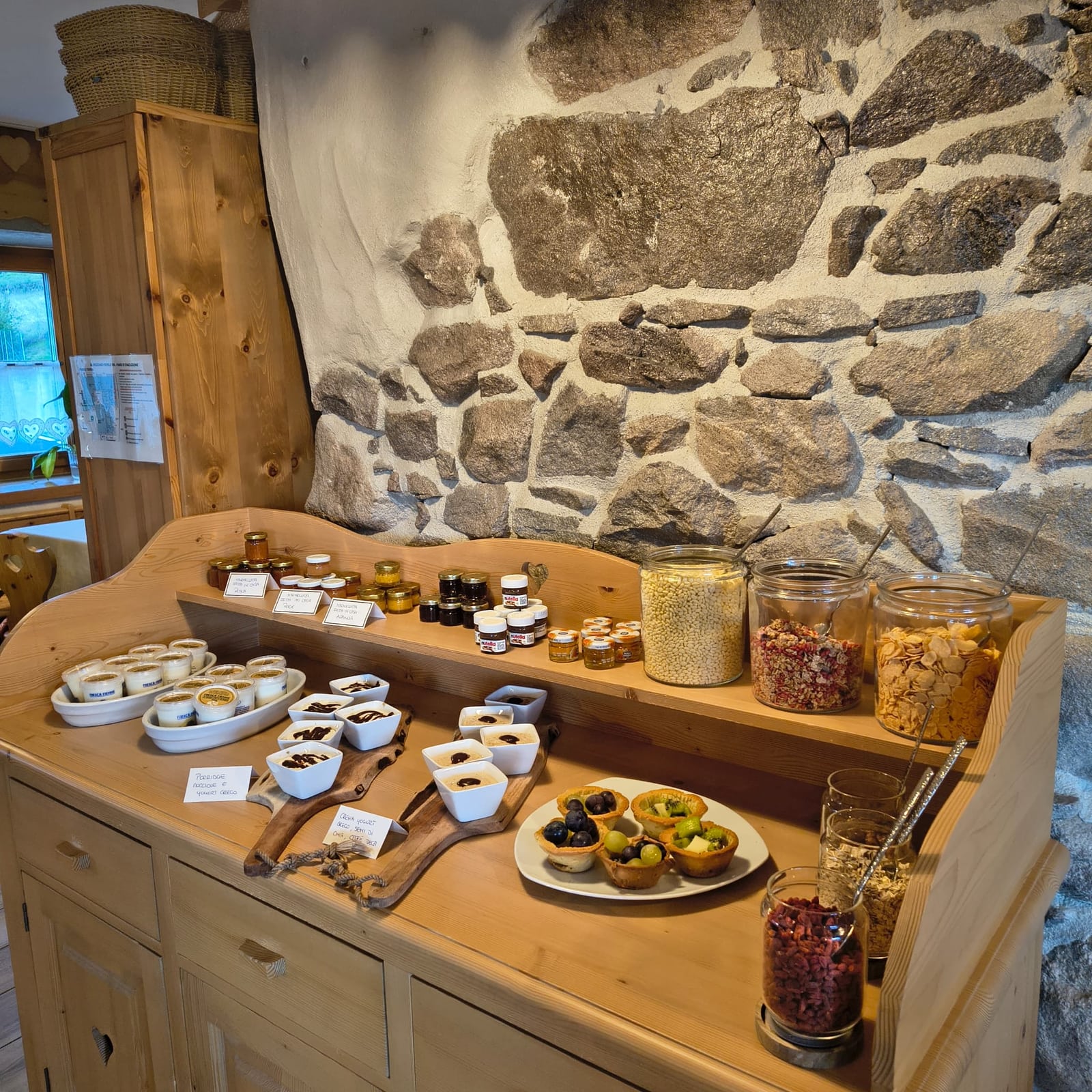 Cereali, yogurt e crostatine alla frutta sul mobile in legno della sala colazioni