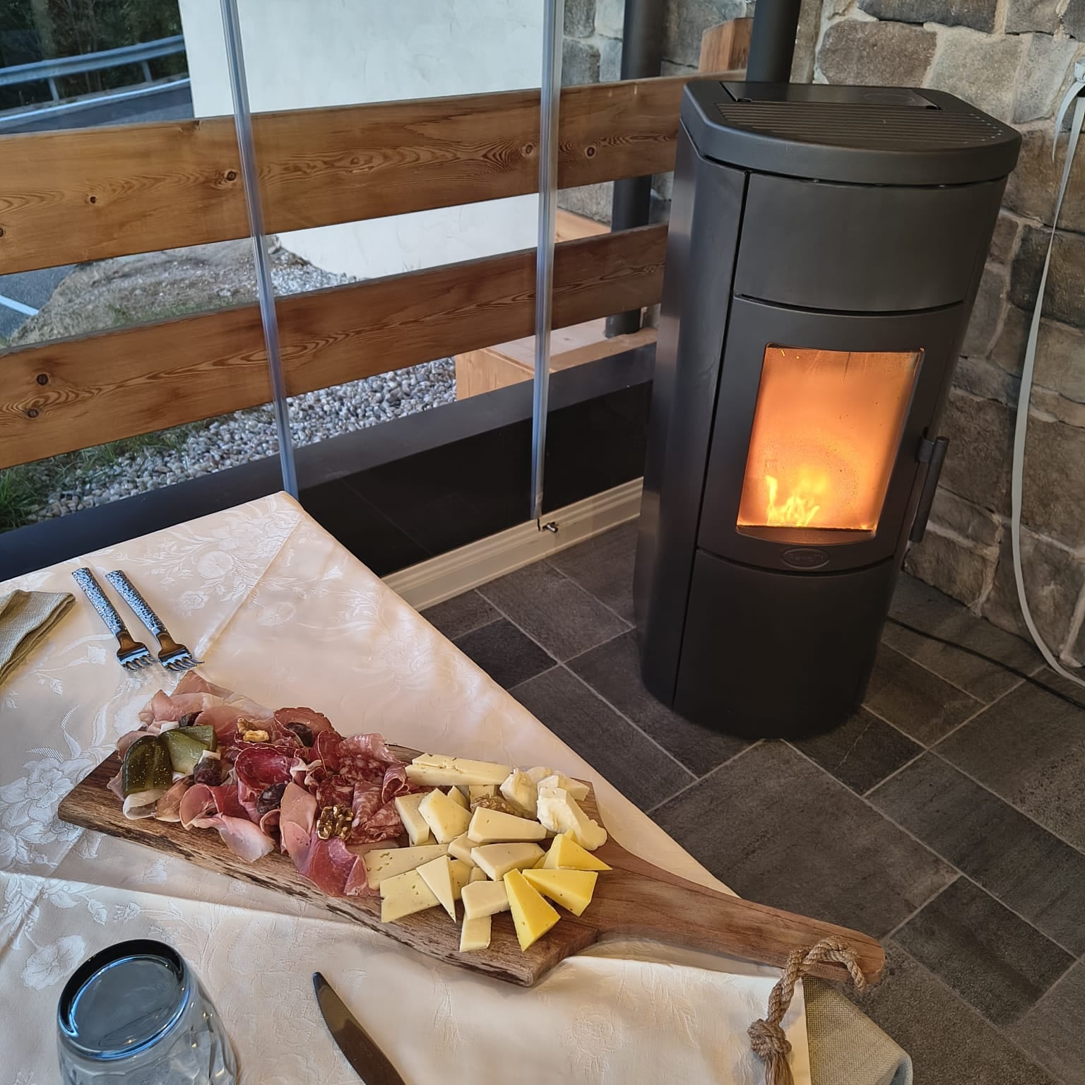 Tagliere di salumi e formaggi accanto alla stufa accesa nella terrazza vetrata