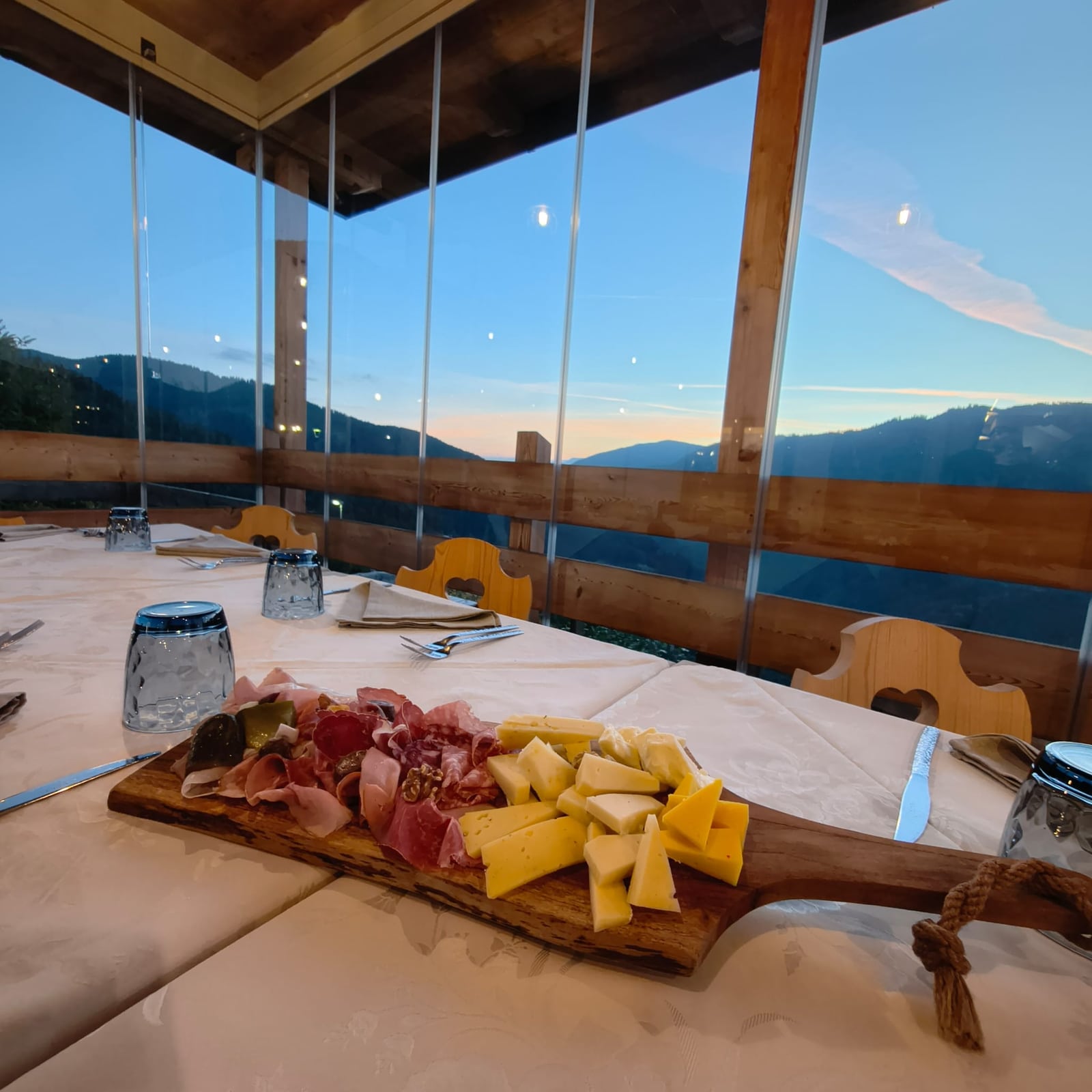 Tagliere di salumi e formaggi sulla terrazza vetrata di Al Vecchio Fienile, con vista sulle montagne al tramonto