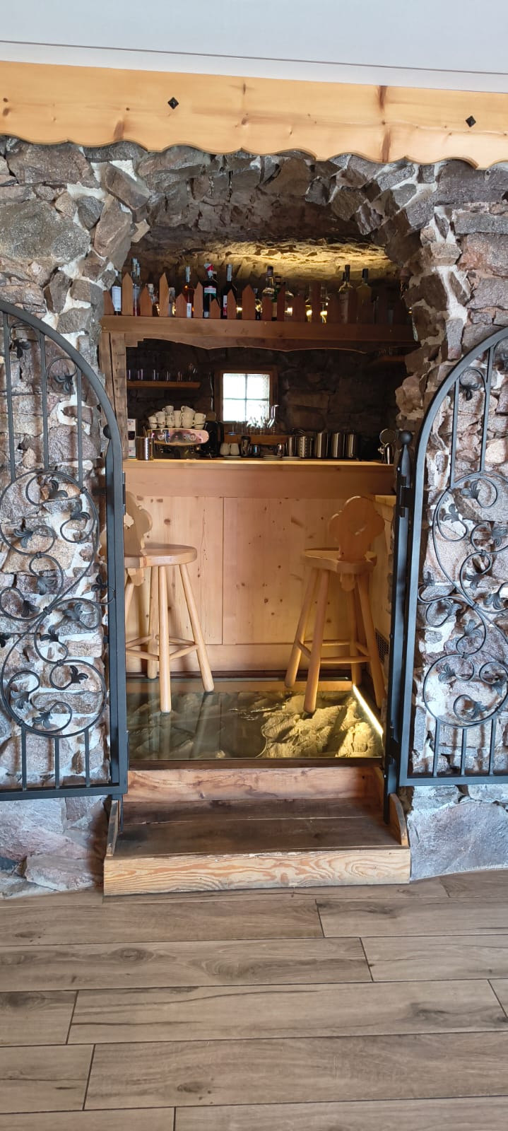 Ingresso al bar sotto la volta in pietra, con bancone e sgabelli in legno
