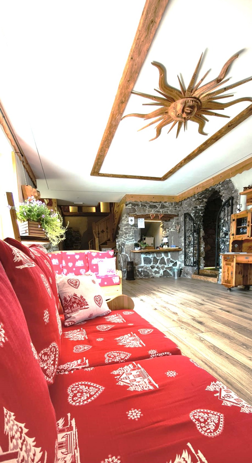 Divani rossi del salotto con decorazione a sole in legno e reception