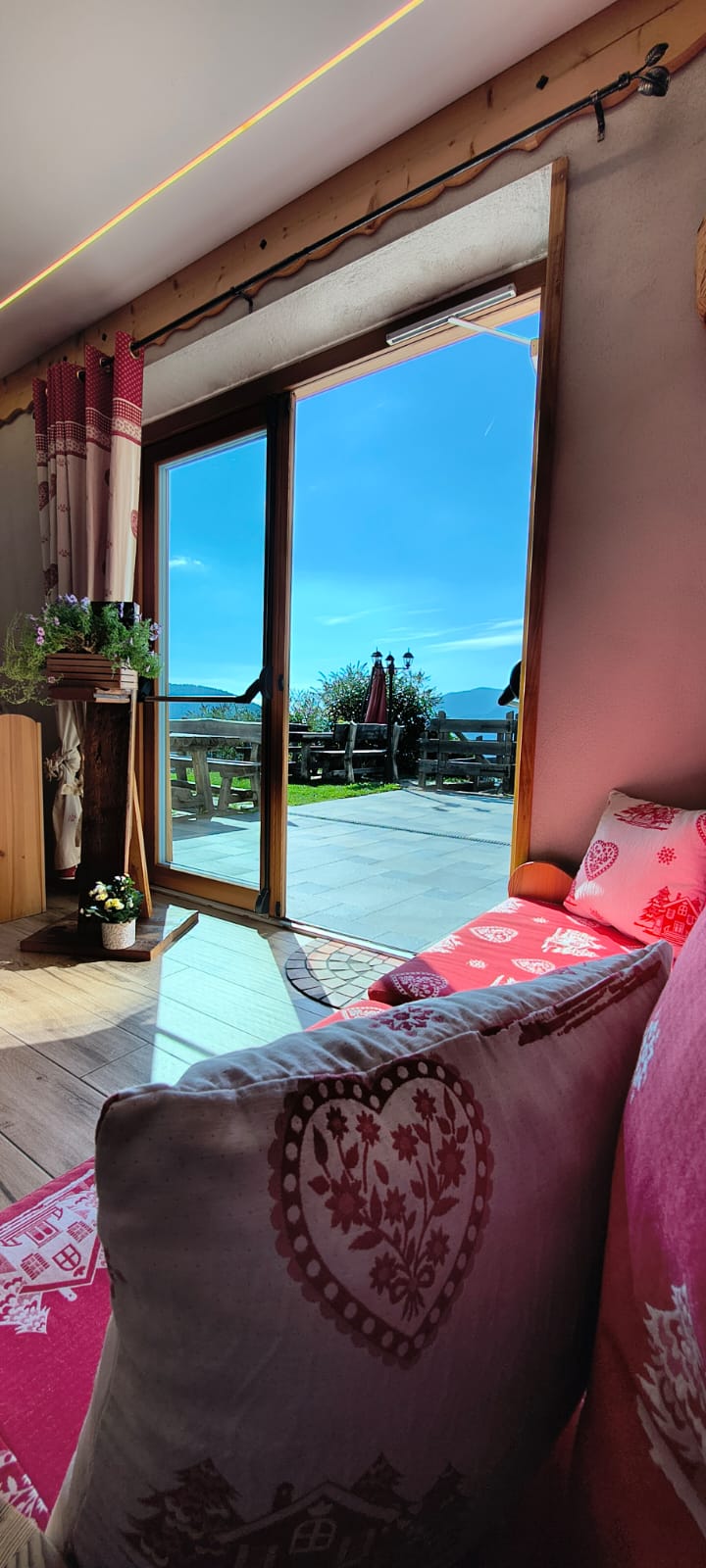Divano con cuscini alpini e vista sulla terrazza e sulle montagne